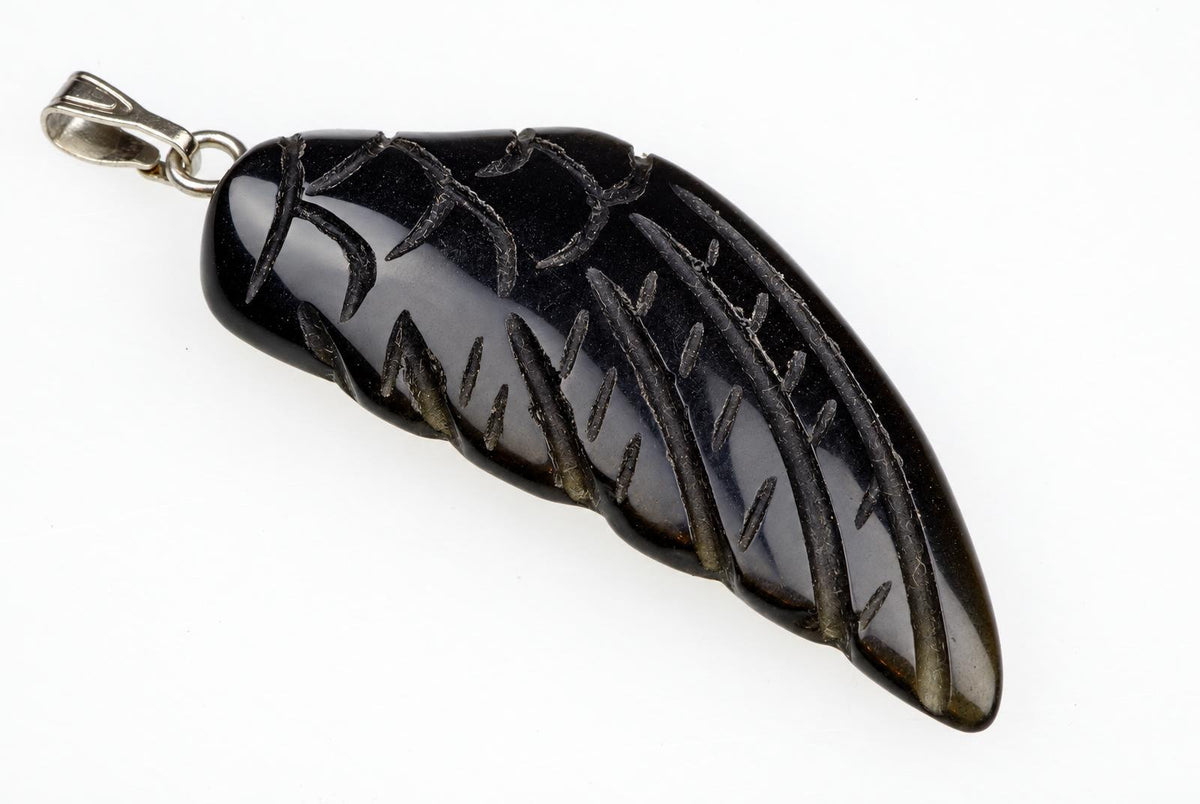 A black onyx pendant shaped like a wing, with carved feather details and a silver-toned bail, set against a white background.