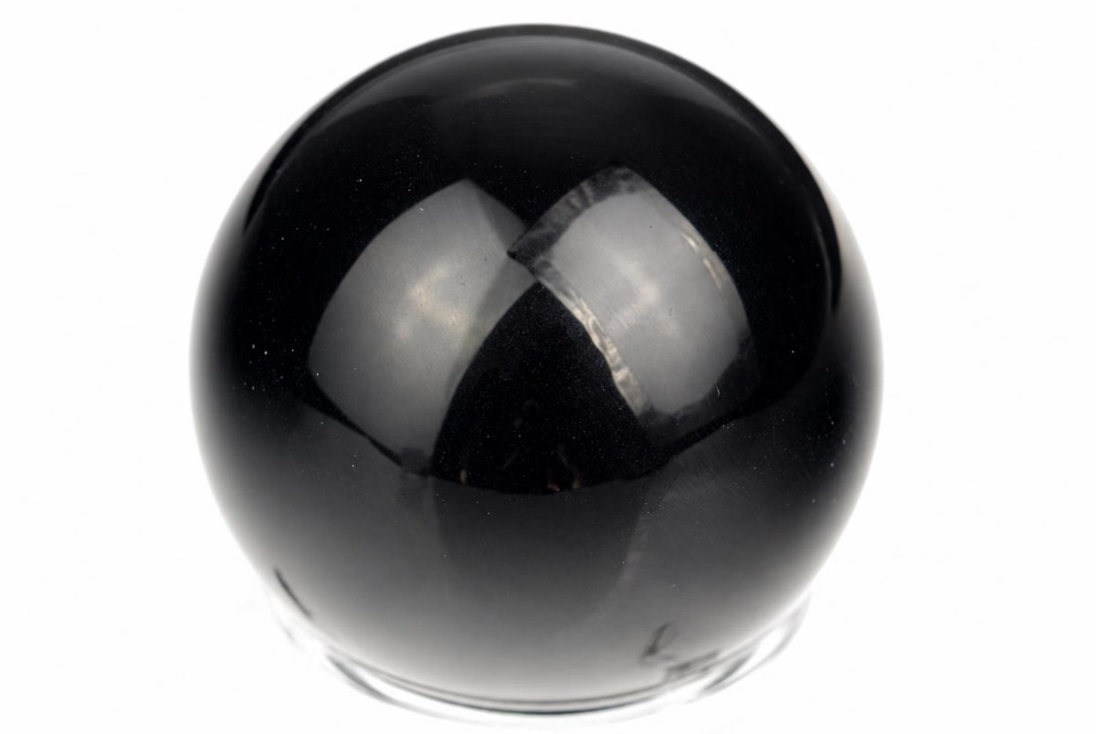 A polished black sphere with a smooth, reflective surface sits on a clear base against a white background.