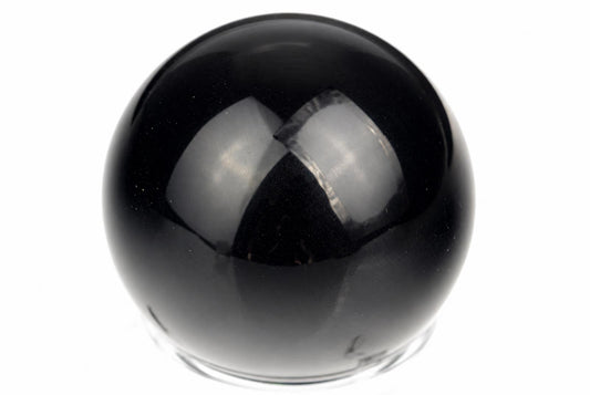 A polished black sphere with a smooth, reflective surface sits on a clear base against a white background.