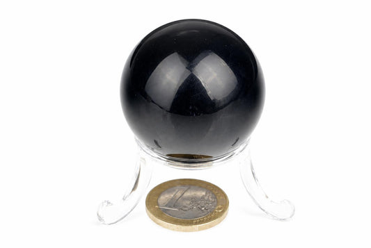 A black sphere on a clear stand with a euro coin for scale, set against a white background.