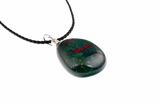 A polished pebble-shaped pendant with dark green and red inclusions hangs from a black cord against a white background.