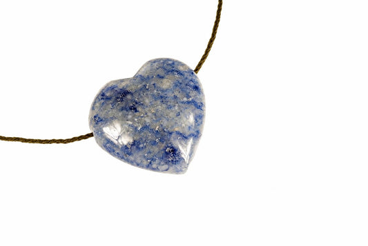 A polished heart-shaped pendant with blue and white speckled patterns hangs on a brown cord against a plain white background.
