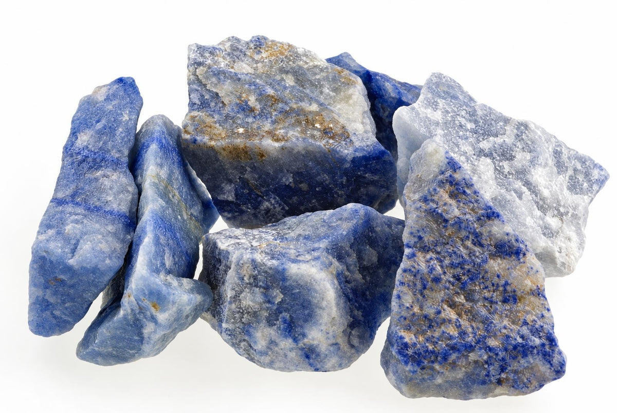 A pile of raw blue quartz stones with white and brown inclusions on a pale surface.
