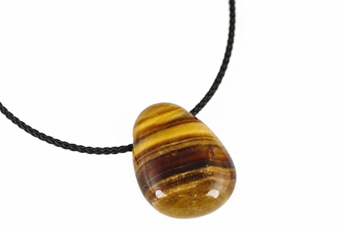 A polished teardrop pendant with horizontal brown and yellow stripes hangs from a black cord against a white background.