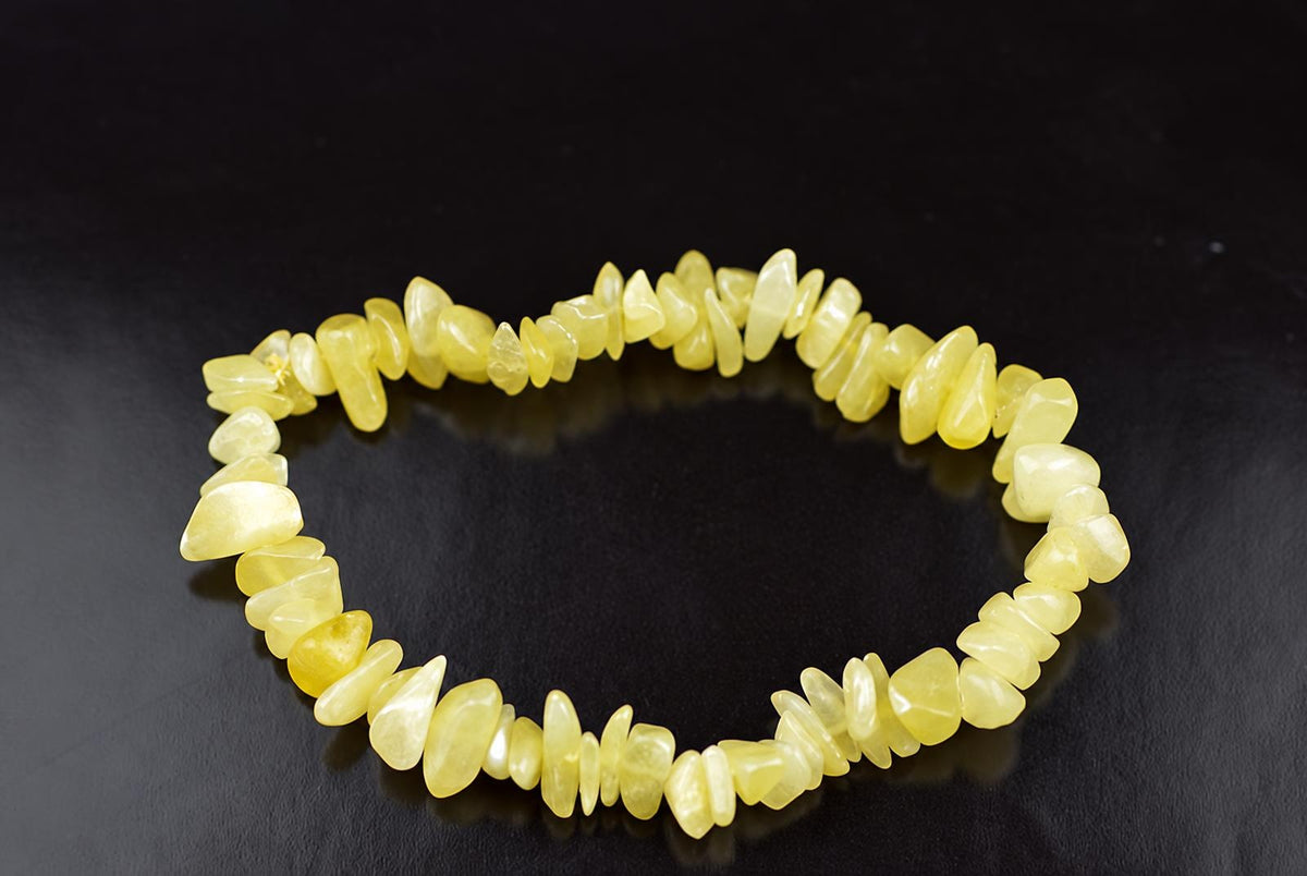 A bracelet made of irregular, polished yellow chips arranged in a circle on a dark surface.