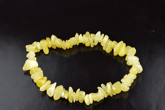 A bracelet made of irregular, polished yellow chips arranged in a circle on a dark surface.