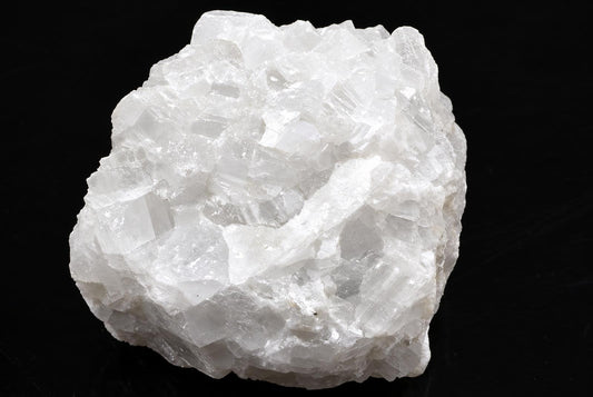 A cluster of white, translucent calcite crystals on a dark surface.