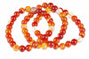 A coiled bracelet of round beads in red, orange, yellow and cream tones on a white background.