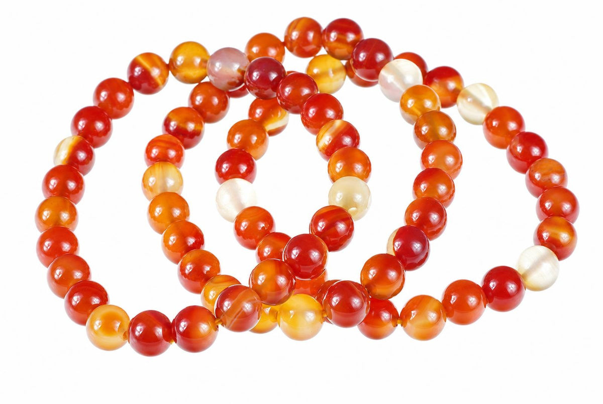 A coiled bracelet of round beads in red, orange, yellow and cream tones on a white background.