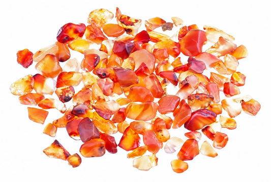A pile of small, polished carnelian stones in shades of orange, red and yellow on a white background.