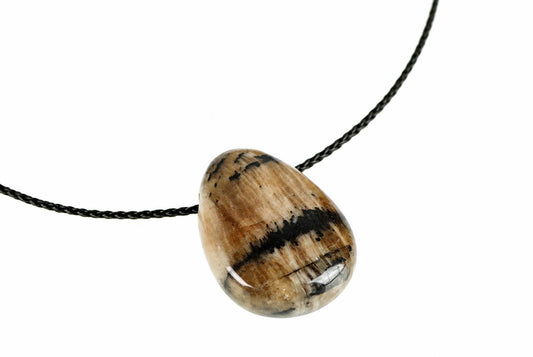 A polished teardrop pendant with brown, black and white stripes hangs on a dark cord against a pale surface.