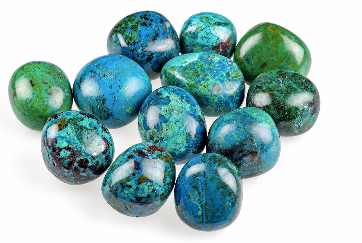 A group of polished, rounded Chrysocolla stones in blue and green with white patches on a pale surface.