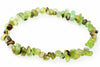 A bracelet made of irregular chips in light green, dark brown and pale tones arranged on a white surface.