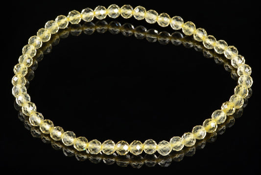 A bracelet of faceted, pale yellow beads arranged in a circle on a dark surface.