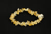 A bracelet made of irregular citrine chips in yellow and pale tones, strung together on a dark surface.