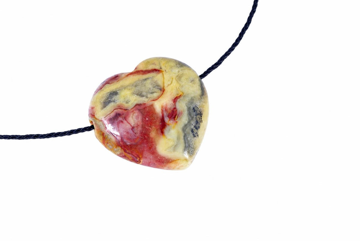 A heart-shaped pendant with swirling red, yellow and grey patterns on a dark cord against a white background.