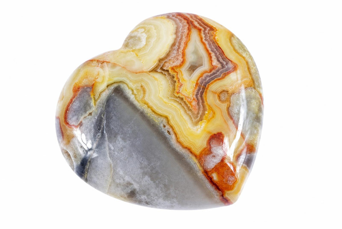 A polished heart-shaped stone with swirling bands of cream, orange, brown and grey on a white background.