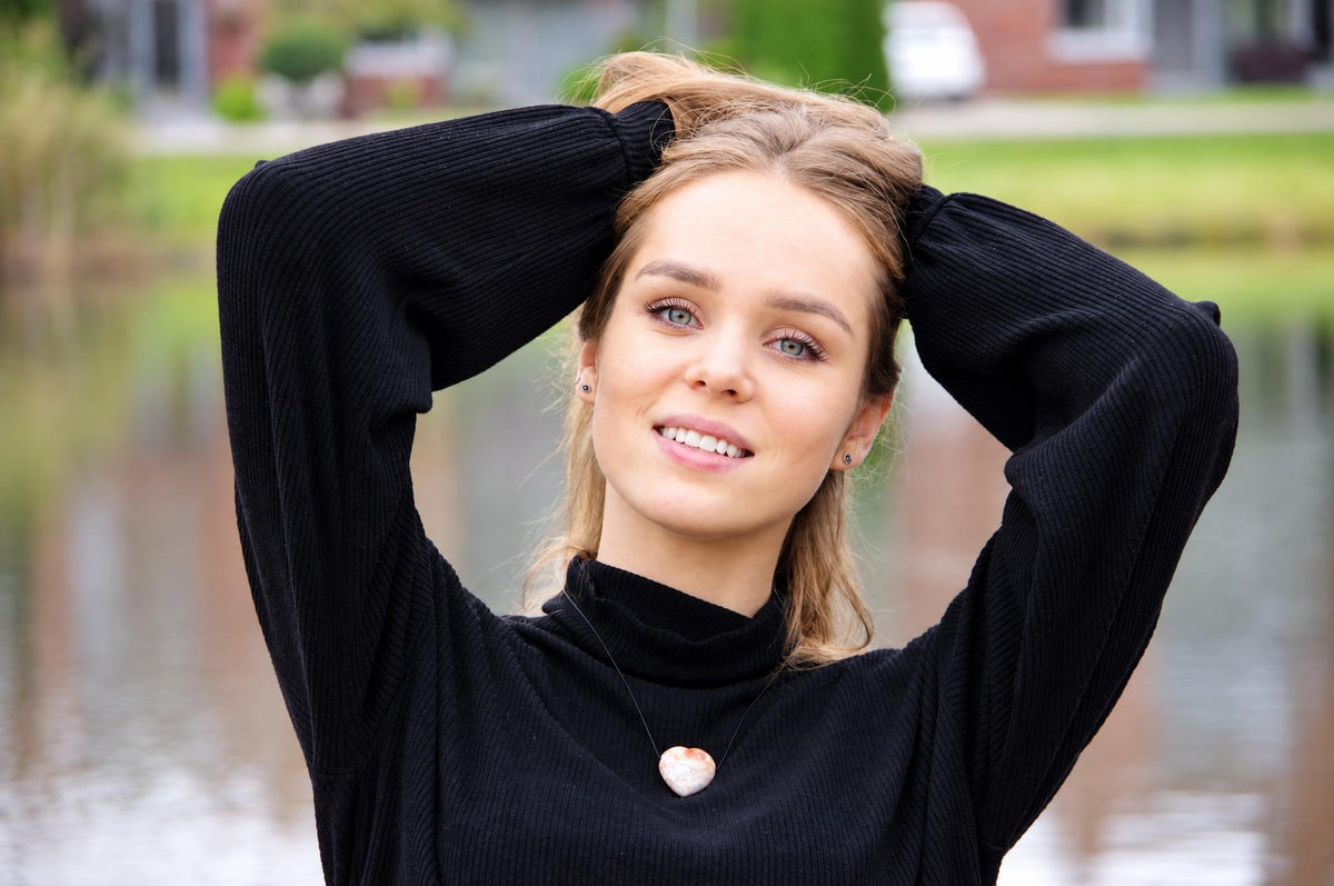 A woman wears a black turtleneck sweater with a heart-shaped Crazy lace agate pendant on a thin cord.