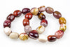 Polished rounded bead bracelet arranged in overlapping loops on a white background, with burgundy, rust red, mustard yellow, cream and mauve beads showing varied natural markings.