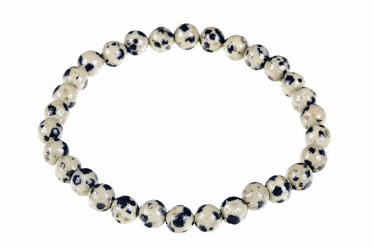 A bracelet made of round beads with a cream background and dark spots, arranged in a circle on a white surface.