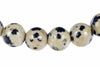 A row of round, cream-coloured beads with black spots on a white background.
