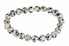 A bracelet made of round beads with a cream background and dark spots, arranged in a circle on a white surface.