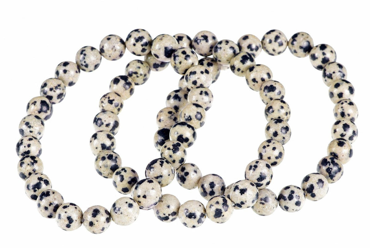 A bracelet of round beads with a cream base and black spots, arranged in loops on a white background.