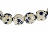 A row of round beads with a pale cream base and dark blue spots, arranged horizontally on a white background.