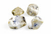 Four polished, rounded stones with white and pale yellow surfaces featuring dark blue and black dendritic patterns on a plain background.