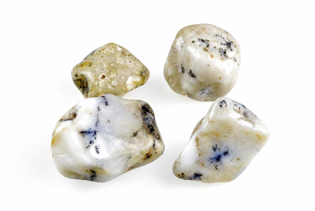 Four polished, rounded stones with white and pale yellow surfaces featuring dark blue and black dendritic patterns on a plain background.