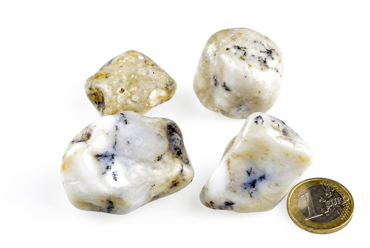 Four polished stones with white, yellow and dark blue patterns on a pale surface next to a coin.