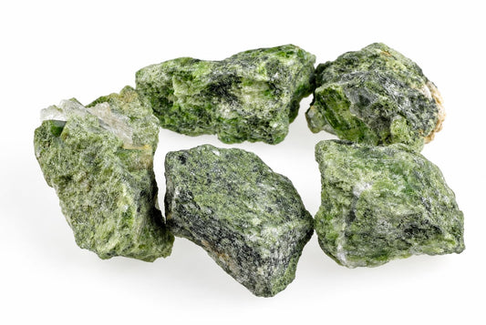 Five rough green mineral specimens with dark and light patches on a white surface.