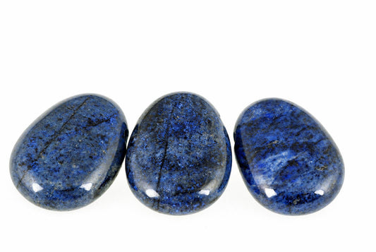 Three polished dumortierite stones in deep blue with dark speckles, arranged horizontally on a white surface.
