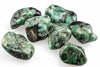 Seven polished green stones with black and white patterns on a pale surface.