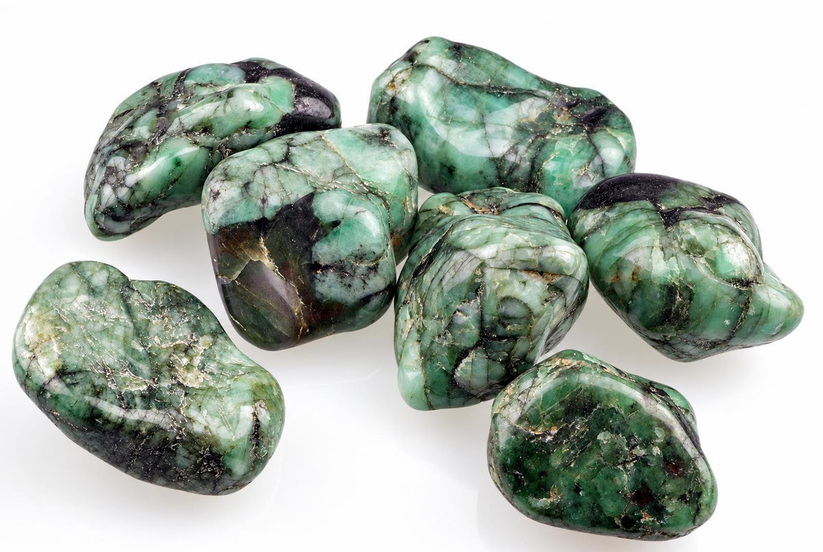 Seven polished green stones with black and white patterns on a pale surface.