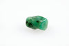 A polished green emerald stone with dark inclusions rests on a white surface.