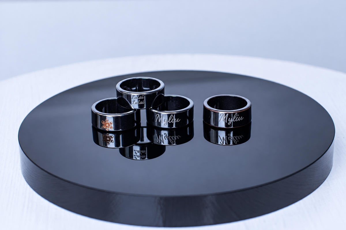 Black rings with light engraved lettering are grouped on a circular dark display surface, with clear reflections beneath them.