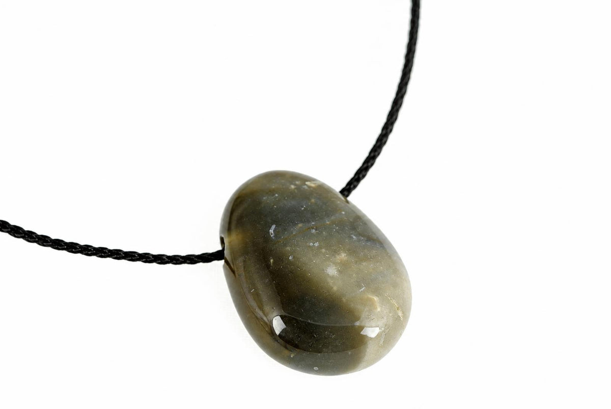 A polished, oval-shaped pendant with a dark green and grey stone on a black cord against a white background.