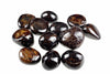A group of polished, dark brown and black stones with golden flecks on a white background.