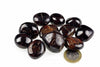 A group of polished, dark brown and black stones with golden-brown inclusions rests on a white surface next to a one-euro coin.