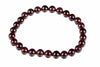 A bracelet made of round, dark red beads with a white background.