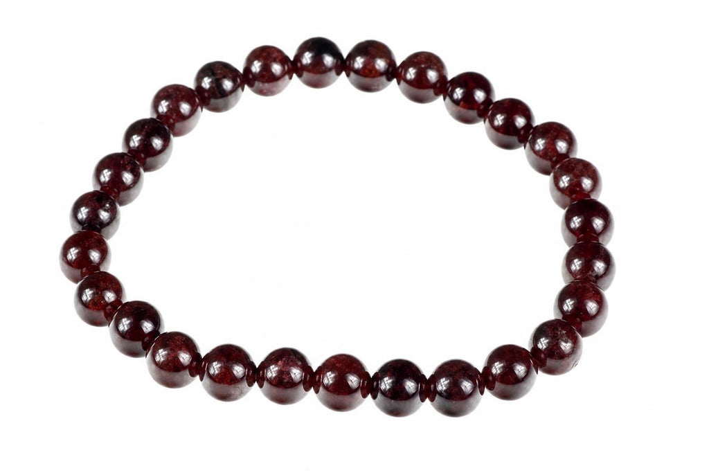 A bracelet made of round, dark red beads with a white background.