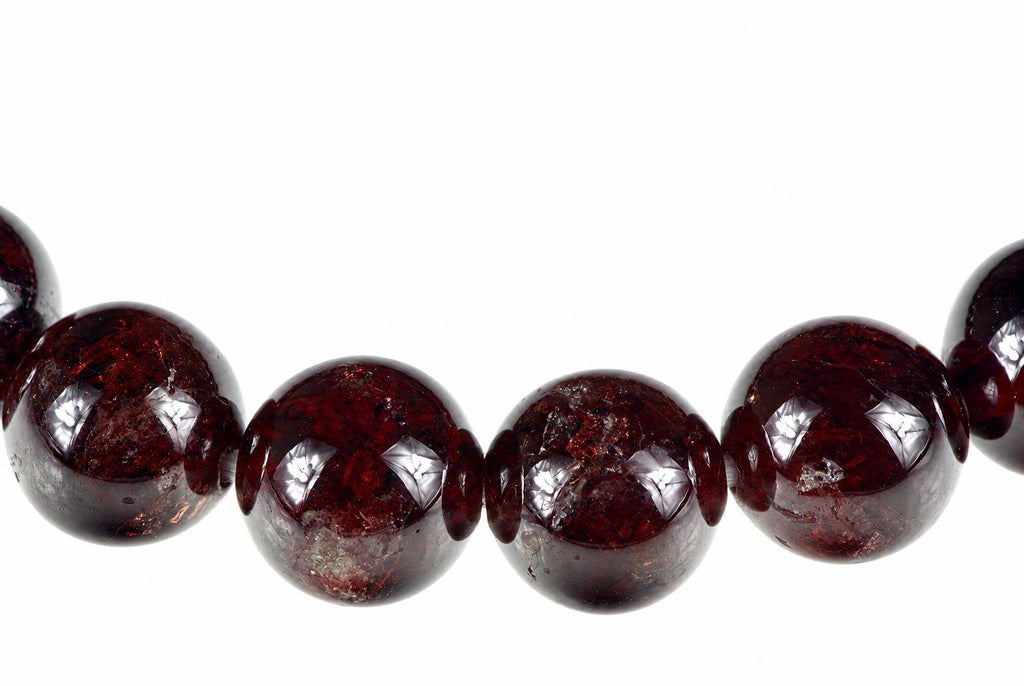A curved row of glossy dark red round beads with bright pale reflections on a white background.