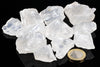 A pile of clear, translucent white crystals on a dark surface with a one-euro coin for scale.