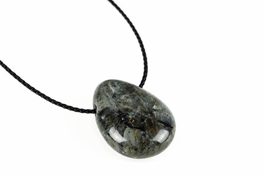 A rounded gray pendant shows irregular black and pale mottling beneath its glossy surface, suspended from a black cord against white.