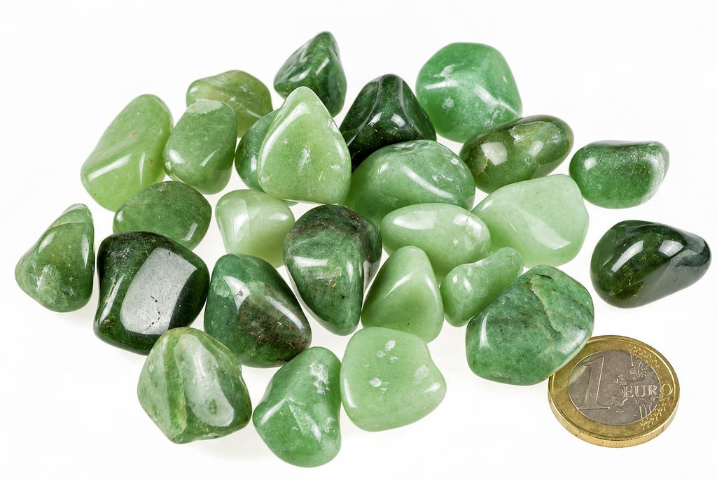 A pile of polished green aventurine stones in various shades, arranged on a white surface with a one euro coin for scale.