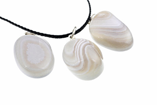 Three polished agate pendants with white and grey banding hang from a black cord against a white background.