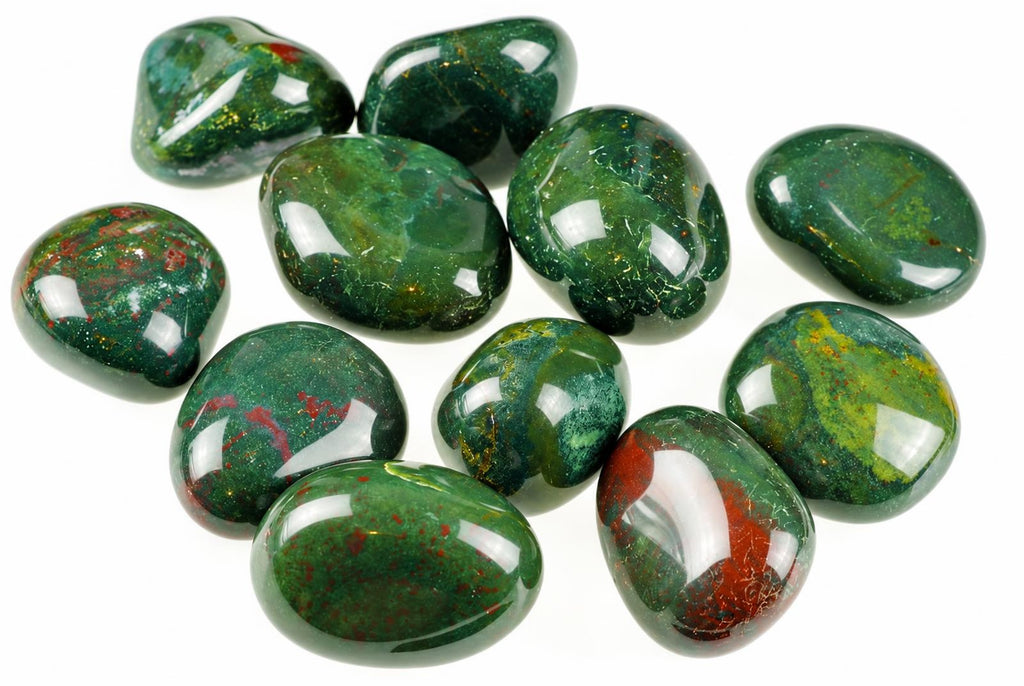 Polished green stones with red patches, yellow flecks and bright reflections are grouped on a white background.