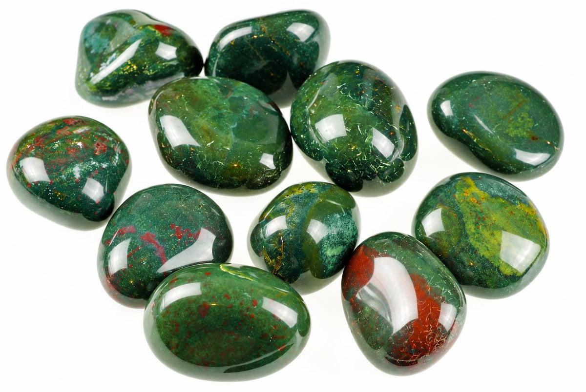 Polished green stones with red patches, yellow flecks and bright reflections are grouped on a white background.