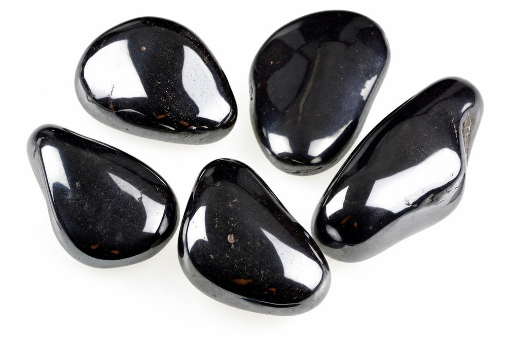 Five polished, dark black stones with a smooth, glossy surface arranged on a white background.